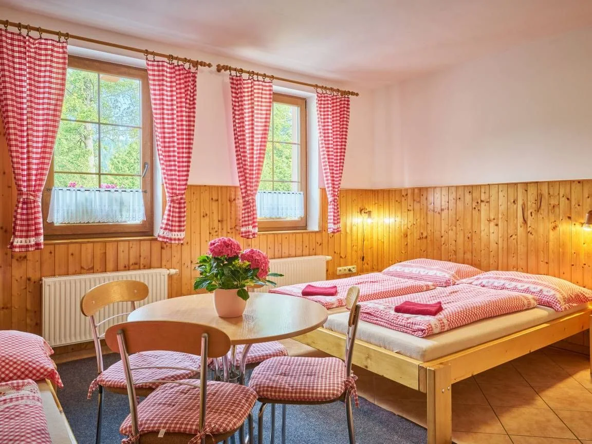 Interiér apartmánu s manželskou postelí, kulatým stolem a dřevěným obložením